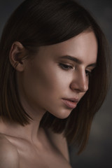 Obraz premium Dramatic portrait of a young beautiful brunette woman with short haircut in the studio.