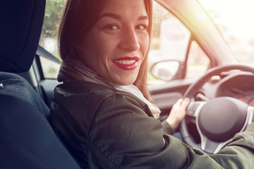 Young smiling woman wearing casual clothes sitting at the wheel of car