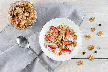 Corn flakes with yogurt in a plate. To the flakes were added dried fruits and strawberries. Near...