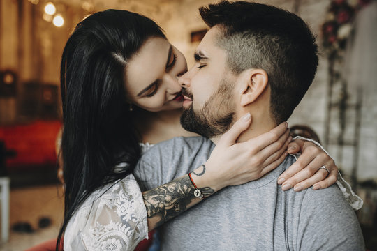 Close up portrait of a amazing couple where tattooed girl is embraing from back with closed eyes his bearded man smiling.