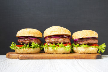 Burgers with beef cutlets on wooden board. Side view. Closeup.