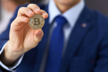 Businessman holding golden bitcoin and smiling. Virtual anonymous money concept, success in digital finance