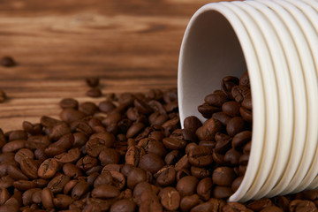 Take away coffee paper cups and roasted coffee beans on rustic wooden table background, close-up.