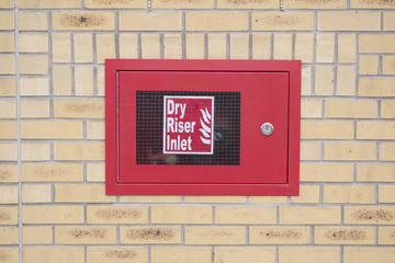 Dry riser inlet box red on brick wall for emergency fire services water connection for hose brigade...