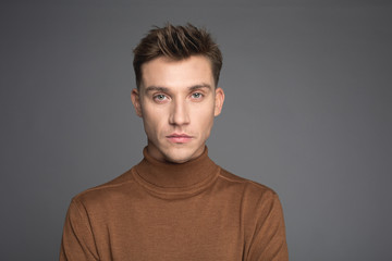 Portrait of gorgeous man staring at camera. His expression is serious. Isolated on background