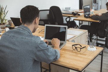 Male typing in notebook computer while sitting at table. He turning back to camera. Worker during...