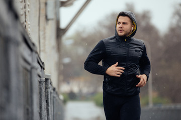 Sports man jogging on the bridge in rainy day