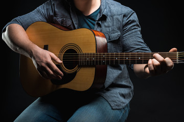 male hands play acoustic guitar