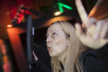 Mujer contenta con una funda de ordenador o documentos celebrando algo. Noche, luces de pub-discoteca al fondo. Fiesta, vida  nocturna