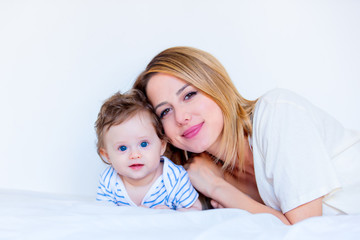 Young mother and little child boy lying down in white bed