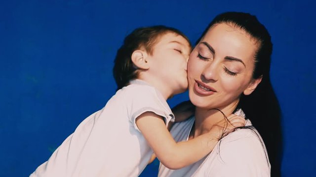 mother and son play laugh and kiss on a blue background