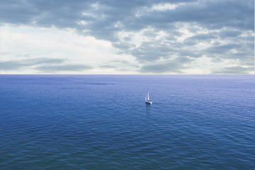 Fototapeta na wymiar Small sailboat entering the immensity of the ocean