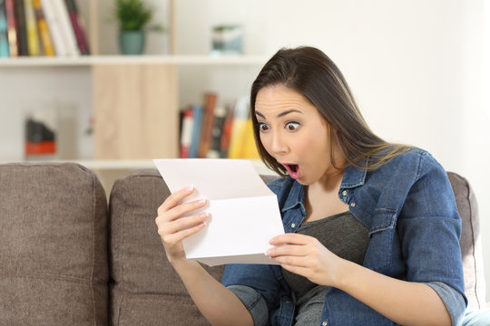 Amazed woman reading surprising news in a letter