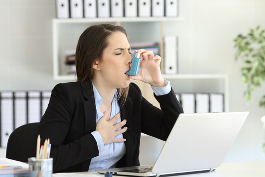 Asmathic executive inhaling with an asthma inhaler