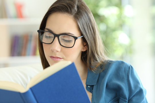 Woman wearing eyeglasses reading a paper book
