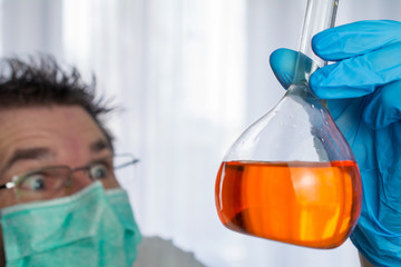 weird looking scientist holds flask with chemical in his hand, concept hazardous substances....