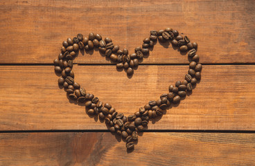 Top view close up heart-shaped aromatic coffee beans locating on desk. Love concept