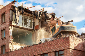 excavator destroys and ruins the building on a bright sunny day