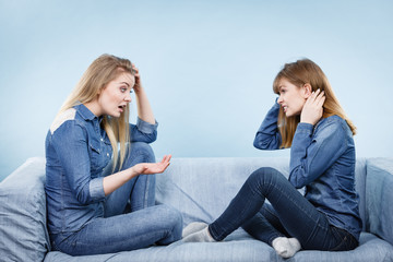Two serious women friends talking on sofa
