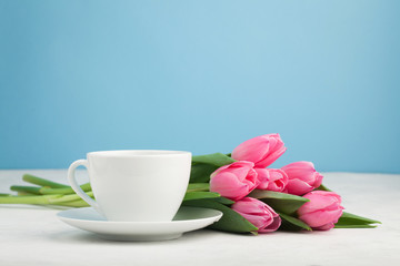 Fototapeta na wymiar Black coffee in white Cup with pink tulips on light stone background