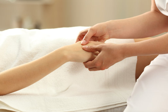 Massage therapist massaging hands of a woman