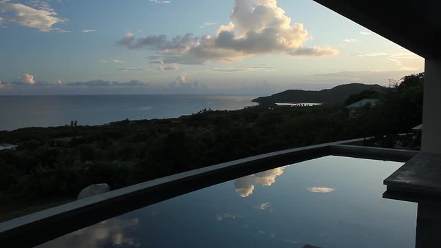Clouds reflected in villa pool with Caribbean view - time lapse