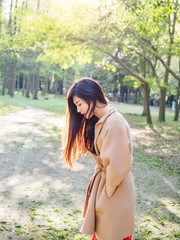 Beautiful girl showing her black long hairs in sunny forest with backlight, Outdoor fashion portrait of glamour young Chinese stylish lady. Emotions, beauty and healthy lifestyle concept.