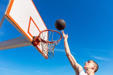 Slam Dunk. Side view of young basketball player making slam dunk © FS-Stock