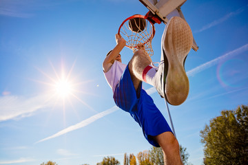 Slam Dunk. Side view of young basketball player making slam dunk © FS-Stock