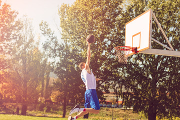 Street basketball player performing power slum dunk