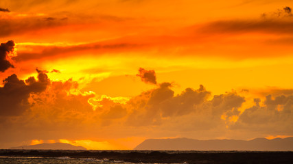 Sunset over sea surface, dark clouds.