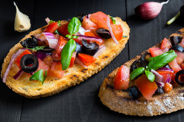 Bruschetta with Tomato and Basil on black wooden boards.