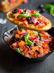 Appetizing bruschetta with Tomato and Basil on black wooden boards.