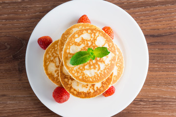 Pancakes (fritters) with strawberries on a plate.