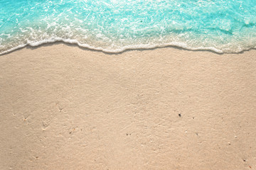 Fototapeta na wymiar Soft waves with foam of blue ocean on the sandy beach