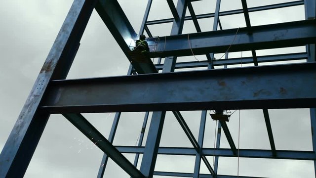 Worker soldering steel beam structure on new building