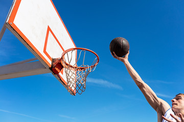 Slam Dunk. Side view of young basketball player making slam dunk © FS-Stock