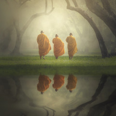 Fantastic scene of asian three monks hiking with reflection the lake in deep forest , Buddha...