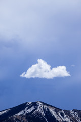A single white cloud above a mountain peak