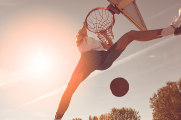 Street basketball player performing power slum dunk