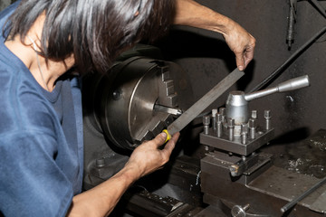 Hands of the man who was used filings with pieces on the lathe. Metalworking industry