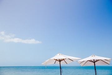 Obraz na płótnie Canvas Vintage white umbrella with the blue sky and blue water.