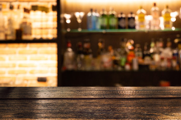 Empty dark wooden bar counter with blur background bottles of restaurant.