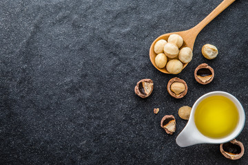  The Macadamia Nut Oil and peeled macadamia nut  on black stone , ﻿use for Healthy Skin and Hair and Natural Healing Oil Treatment , overhead and top view