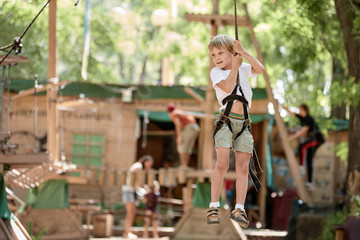 Fototapeta na wymiar Happy boy enjoying summer activity in the rope park