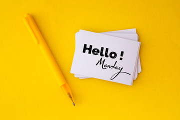 the yellow pen and stacking of white business card with Hello Monday message on vibrant yellow background , cheerful for happy working time Monday concept