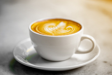 The hot coffee art in the white ceramic mug in the restaurant or coffee shop on the white or gray marble surface.