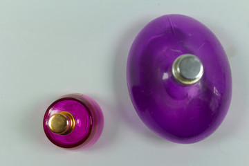 Transparent bottle of female perfume on a colored pink background. Top view. Women's accessories.