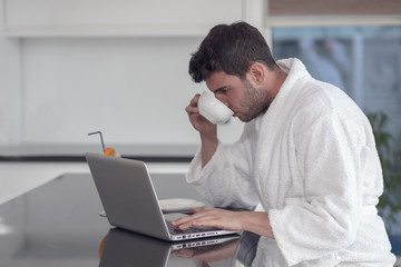 A man in a robe with a laptop at home