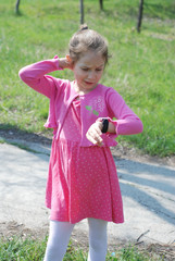 Little girl in pink Dress using smart Watch Pink color. Outside Green Park